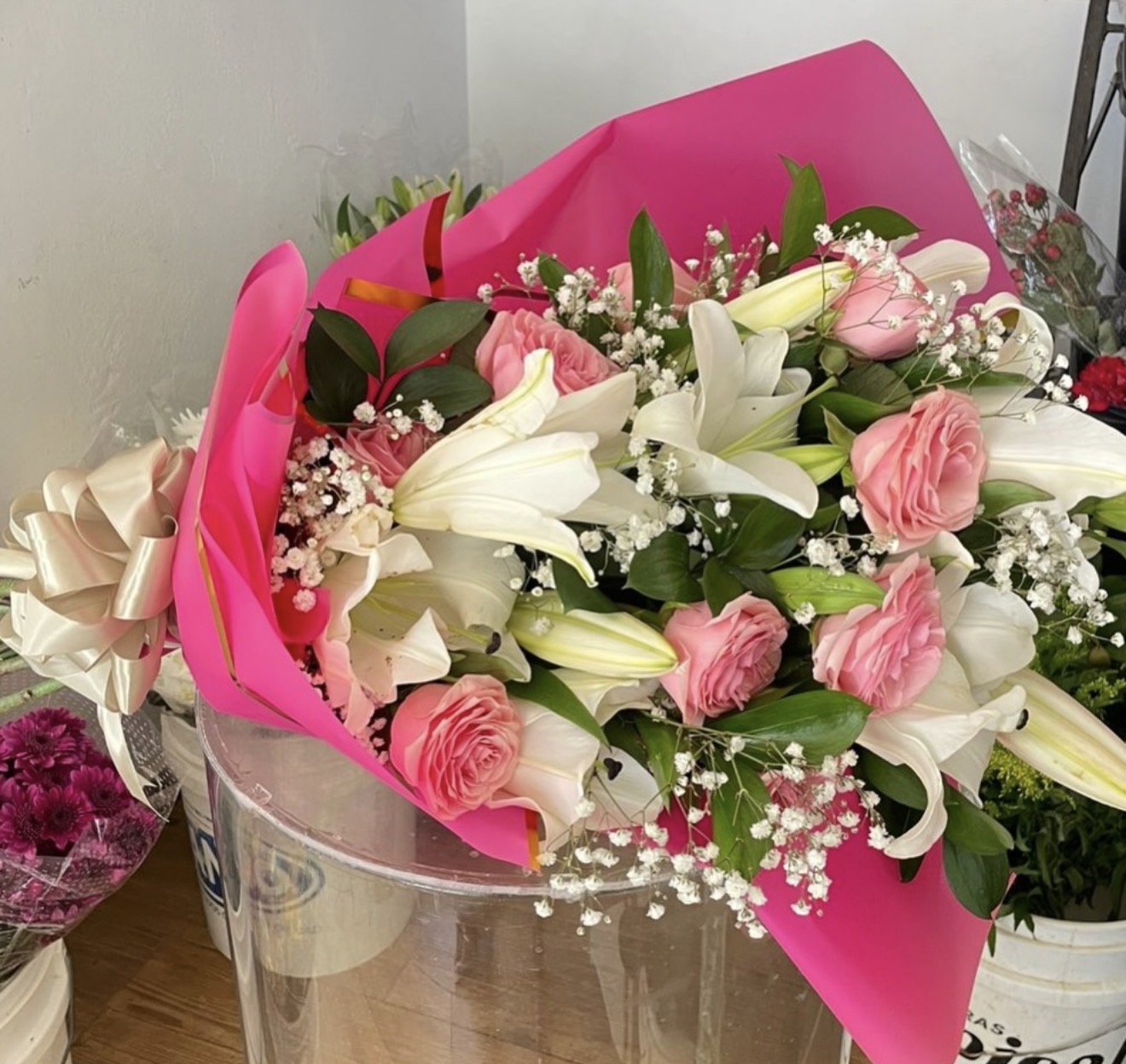 Ramo de lirios blancos y rosas rosadas con envoltura fucsia