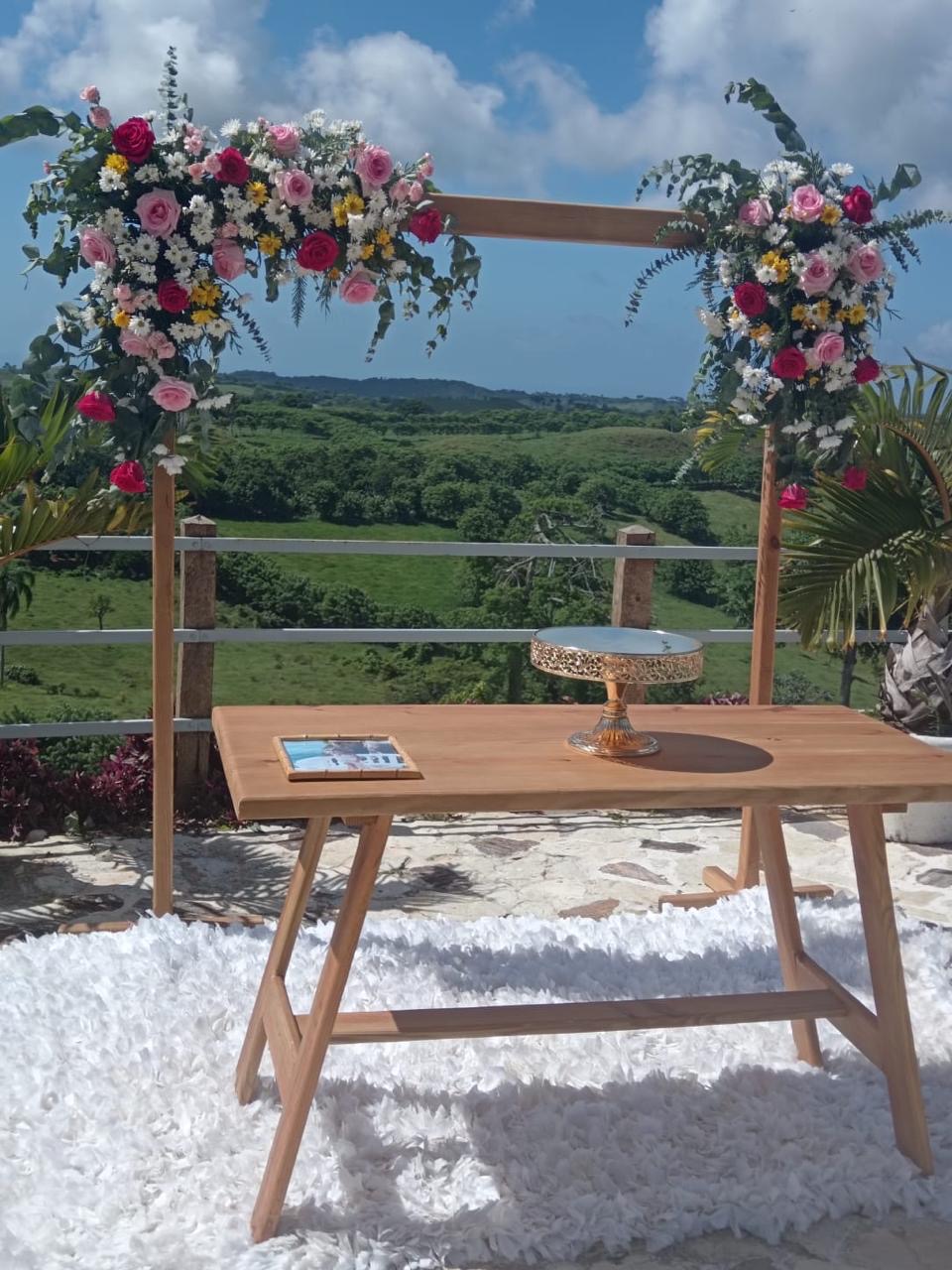 Arco floral colorido con mesa de pastel y vista al campo