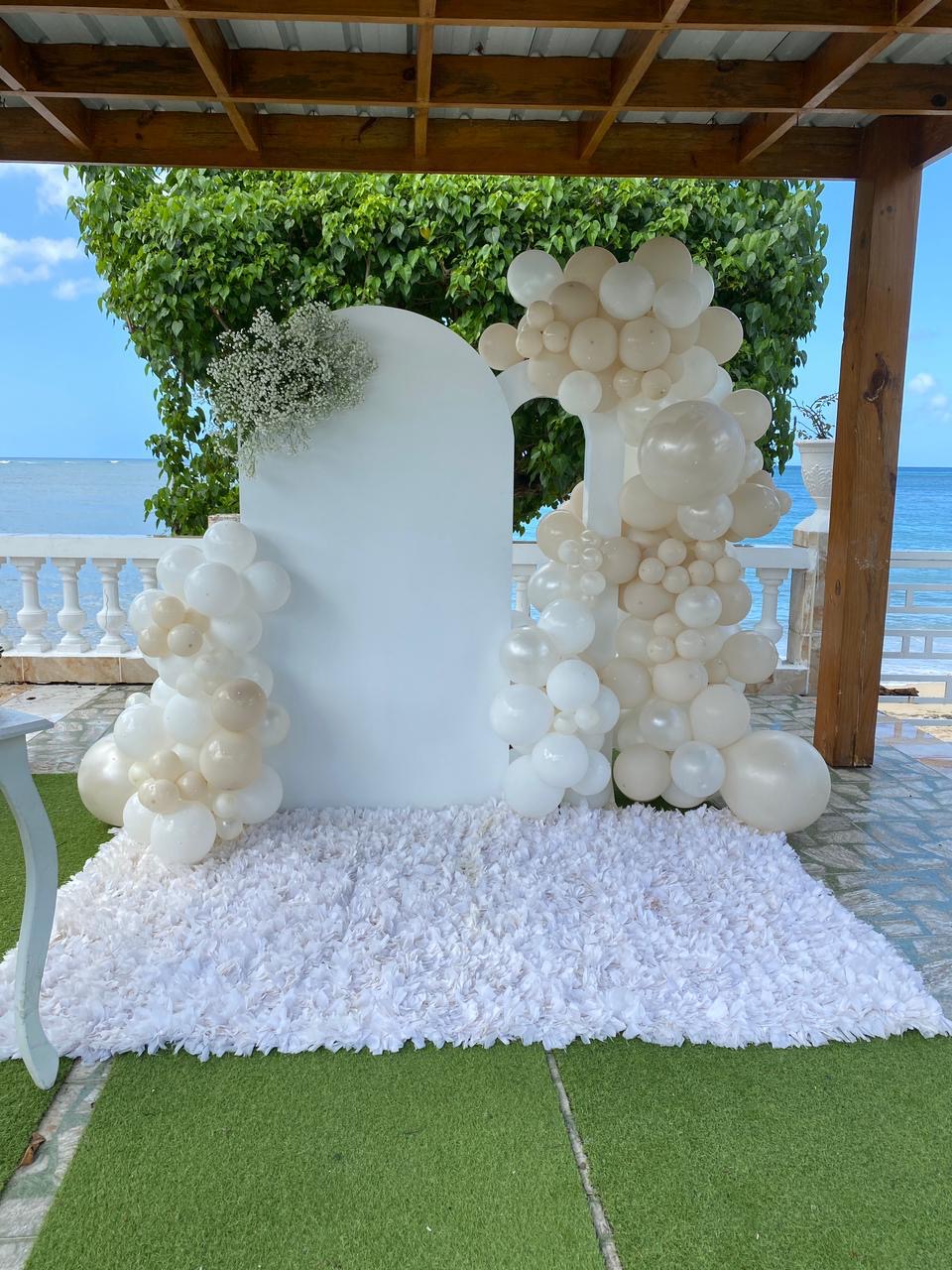 Backdrop con arco de globos blancos frente al mar